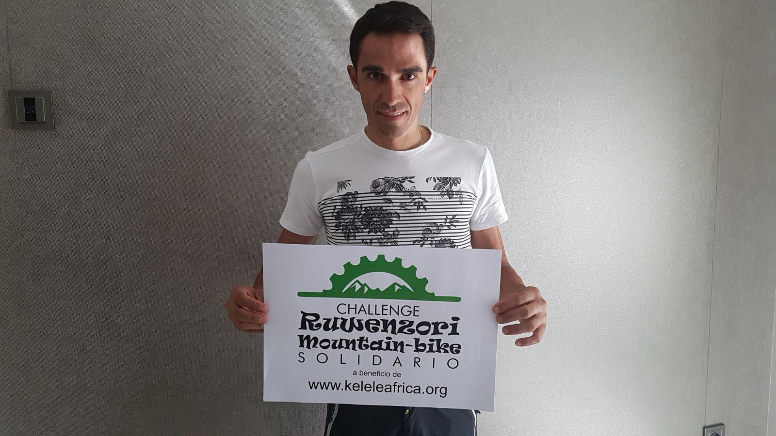 El ciclista Alberto Contador con un cartel del Challenge Ruwenzori Mountain-bike Solidario